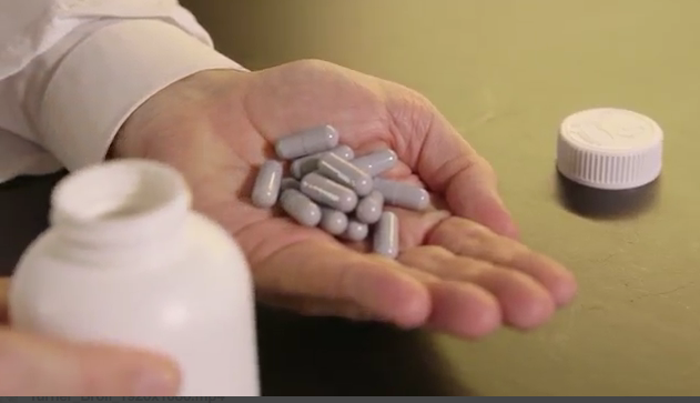 A hand holds a mound of pills