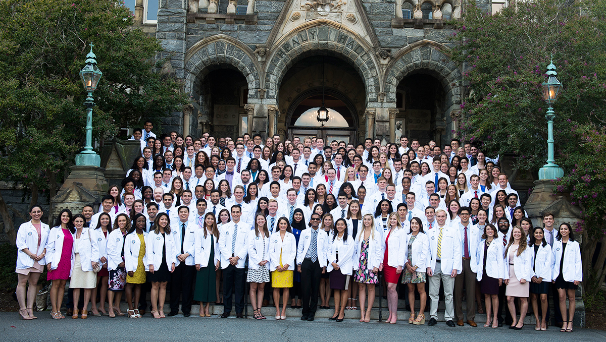 The Class of 2021 at the School of Medicine gathers on the steps of Healy Hall for a photo in their white coats