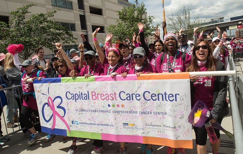 A group of marchers clad in pink celebrates as they finish a charity walk