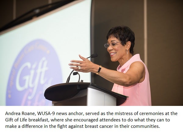 Andrea Roane stands at a podium gesturing while behind her is a screen projecting the words "Gift of Life"