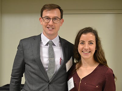 A man and woman stand side by side smiling