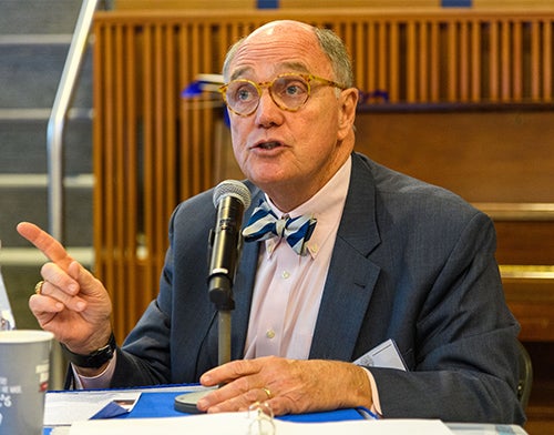 Stephen Ray Mitchell sits at a table speaking into a microphone