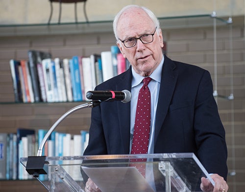 Dr. Edward Healton speaking at a podium, with shelves of books behind him