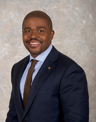 A portrait of Mr. King, who is pictured in suit and tie against a gray background