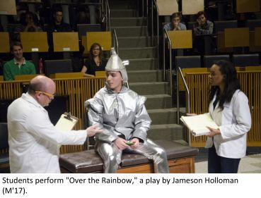 A man dressed like Tin Man from the Wizard of Oz with two doctors with clipboards on each side.