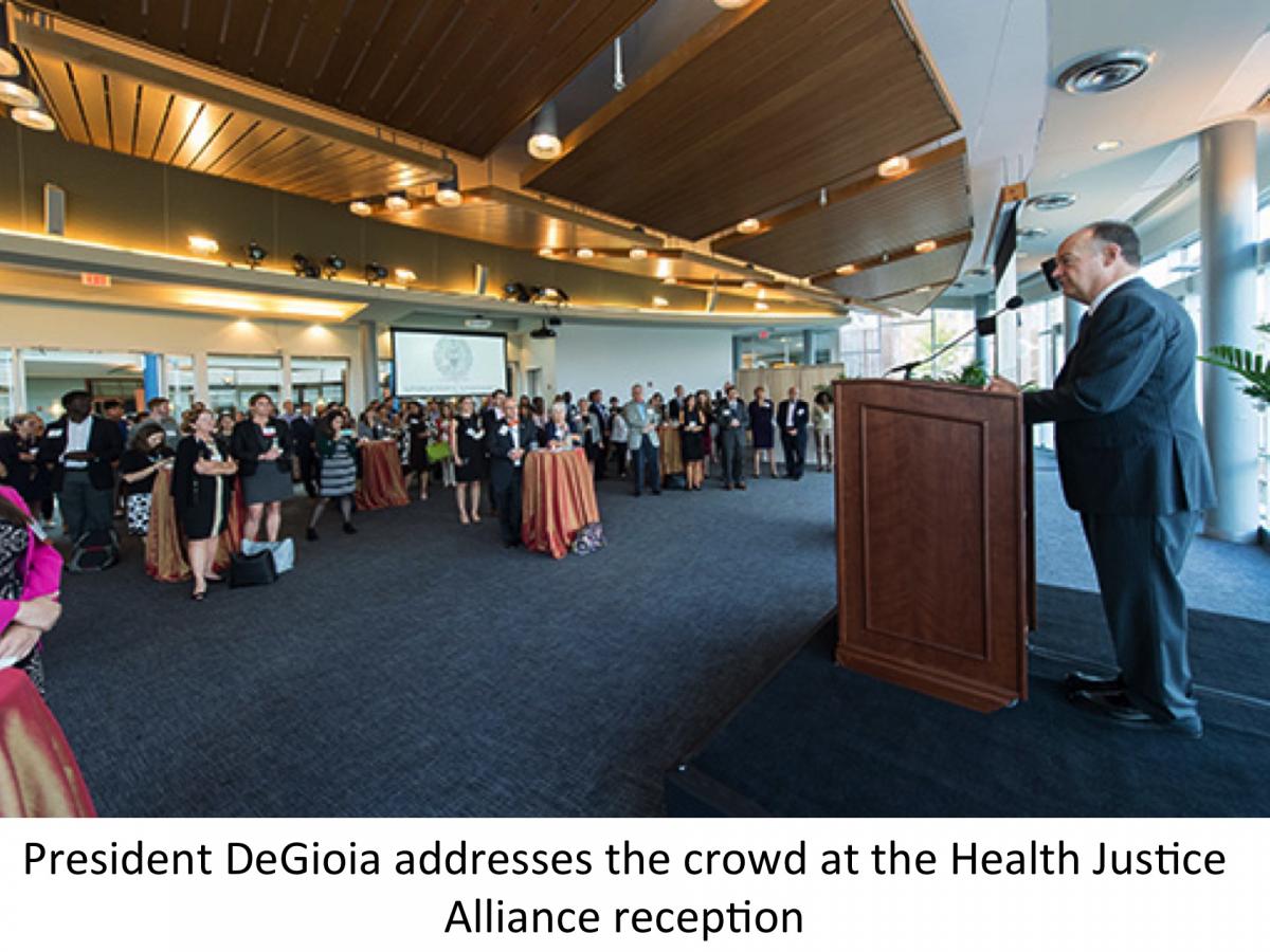 President DeGioia stands at a podium in front of a full room of people