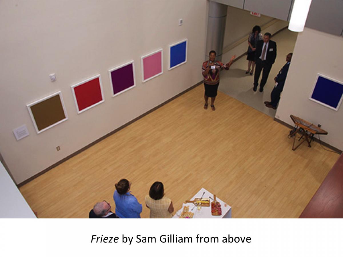 Looking down from above at the installation, 5 solid colored squares on the wall, from left to right, brown, red, purple, pink and blue