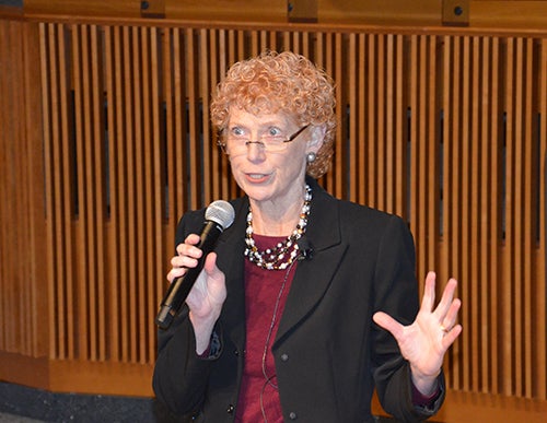 Eileen Moore stands with a microphone in an auditorium