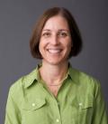 Ms. Girard wears a green shirt and smiles in this portrait image