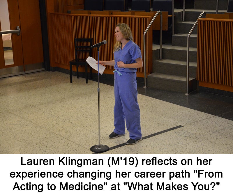 A woman in medical scrubs stands at a microphone holding papers in one hand