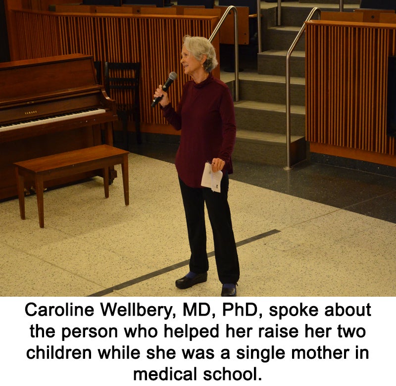 A woman stands alone, holding a microphone in one hand and a piece of paper in the other