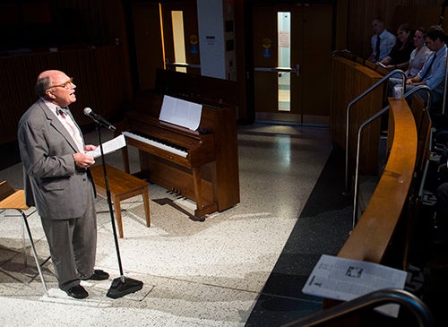 Dean Stephen Ray Mitchell stands at a microphone and speaks to an audience