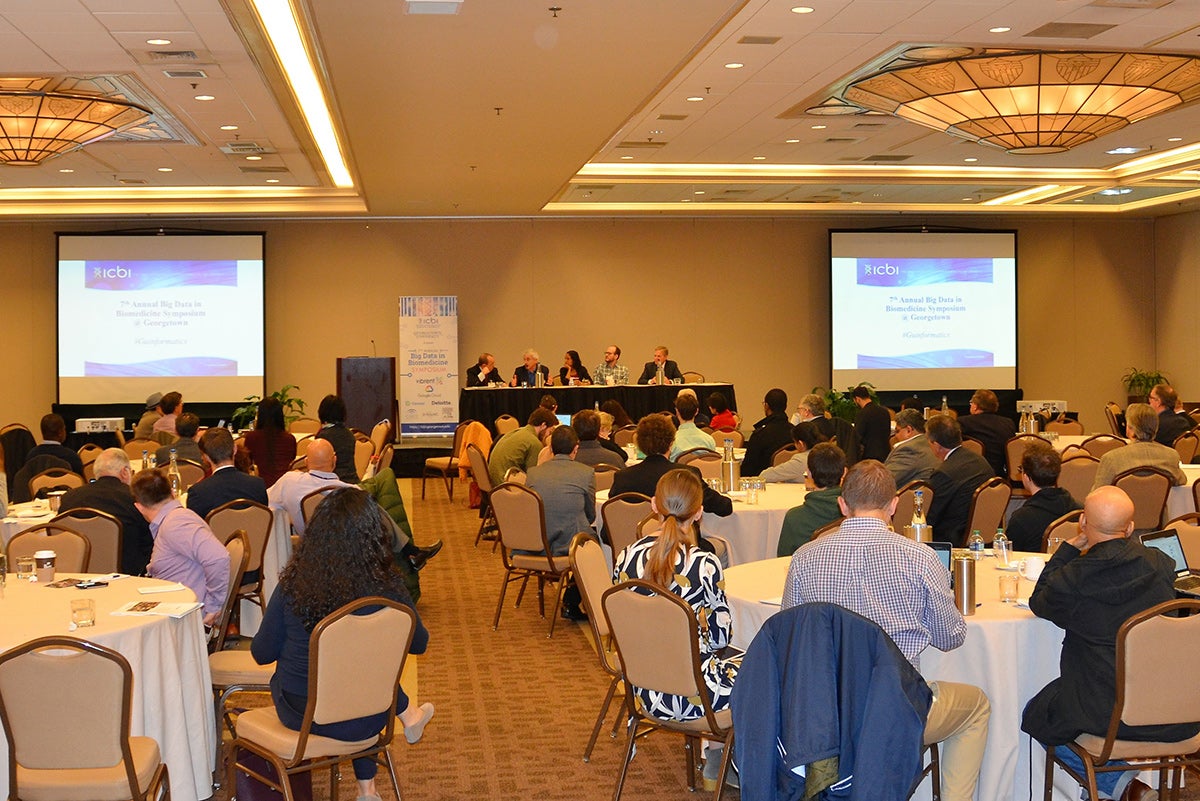 A group sits at a table amid a ballroom full of people seated at round tables