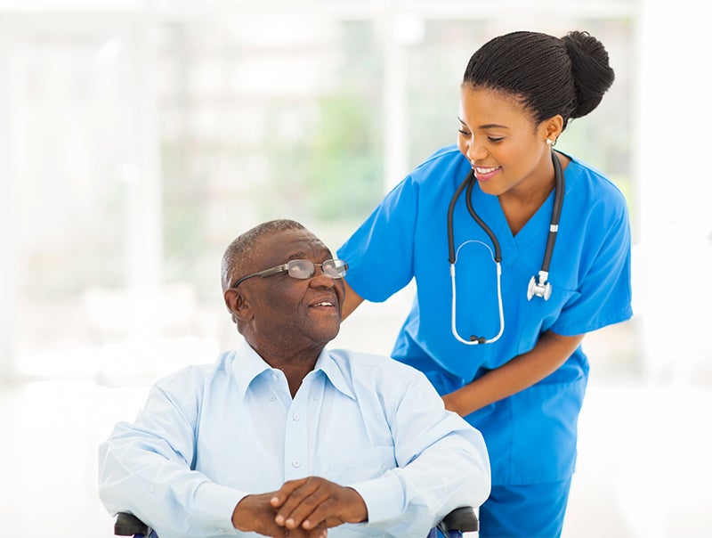 A woman tends to an older man in a wheelchair