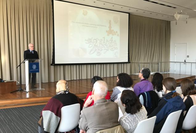 Dr. Edward Healton speaks from a podium on a stage before a seated audience.