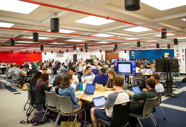 Students work in large groups at tables in the DML