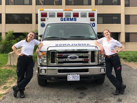 Two women stand on either side of a an ambulence