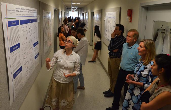 A student presents her poster for onlookers