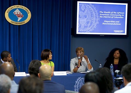 Panelists sit at a table before an audience