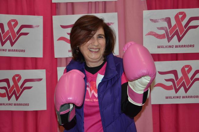 A woman poses in pink boxing gloves.