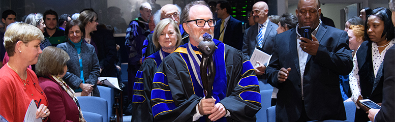 Dr. Elliott Crooke carries a ceremonial mace leading a procession of faculty members at Convocation