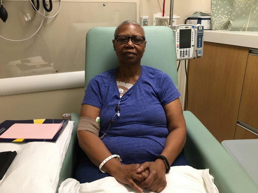 A woman rests in the chair of her hospital room.
