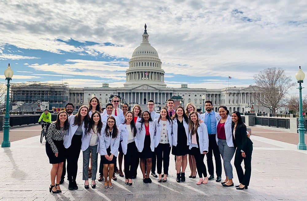 A group of medical students stands outdoors before the U.S. Capitol Building