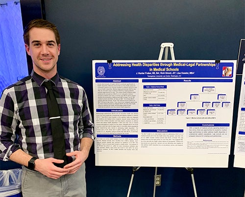 A man stands before an academic poster.