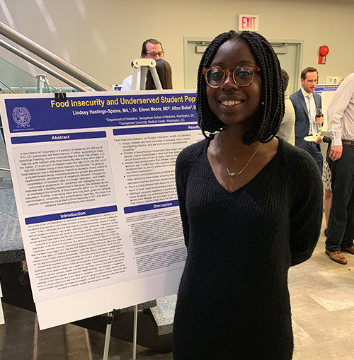 A woman stands before an academic poster.