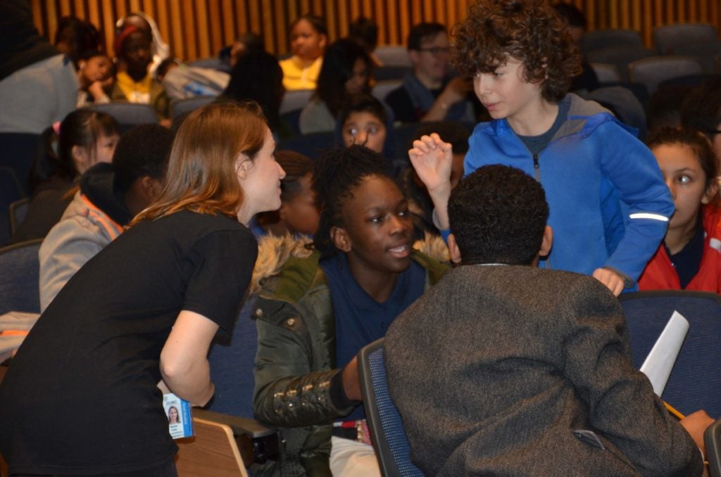 A female graduate student listens carefully to a male middle school student.