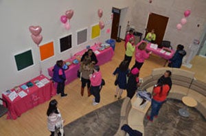 A pink-themed room with balloons and people mingling.
