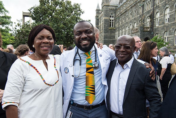 Three people stand side by side outdoors, one of them a medical student