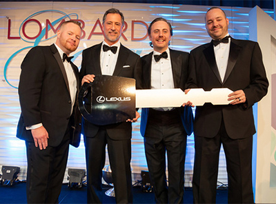 Four men in black tie hold a giant replica key with the Lexus logo on it
