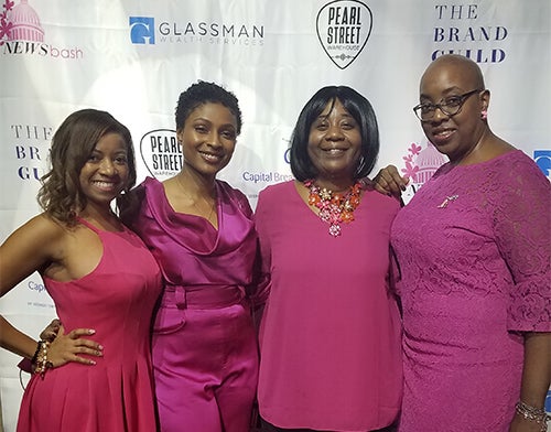 Four women wearing pink stand side by side at the event.