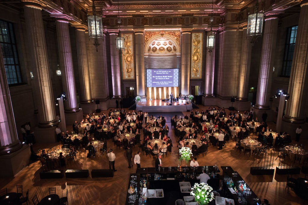 A large room is filled with tables and people for an event.