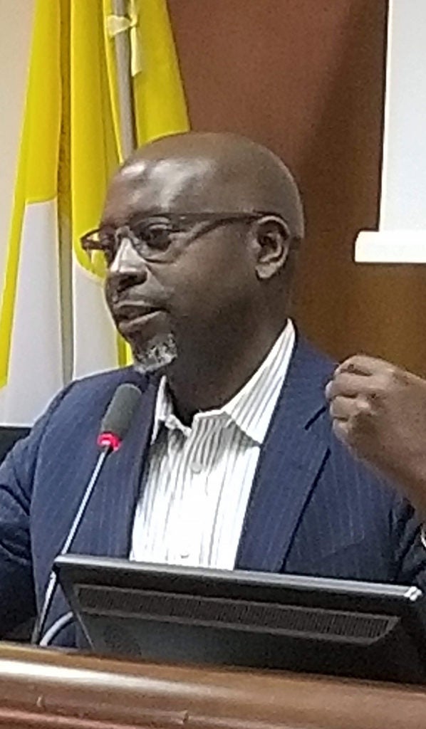 Deus Bazira speaks at a podium