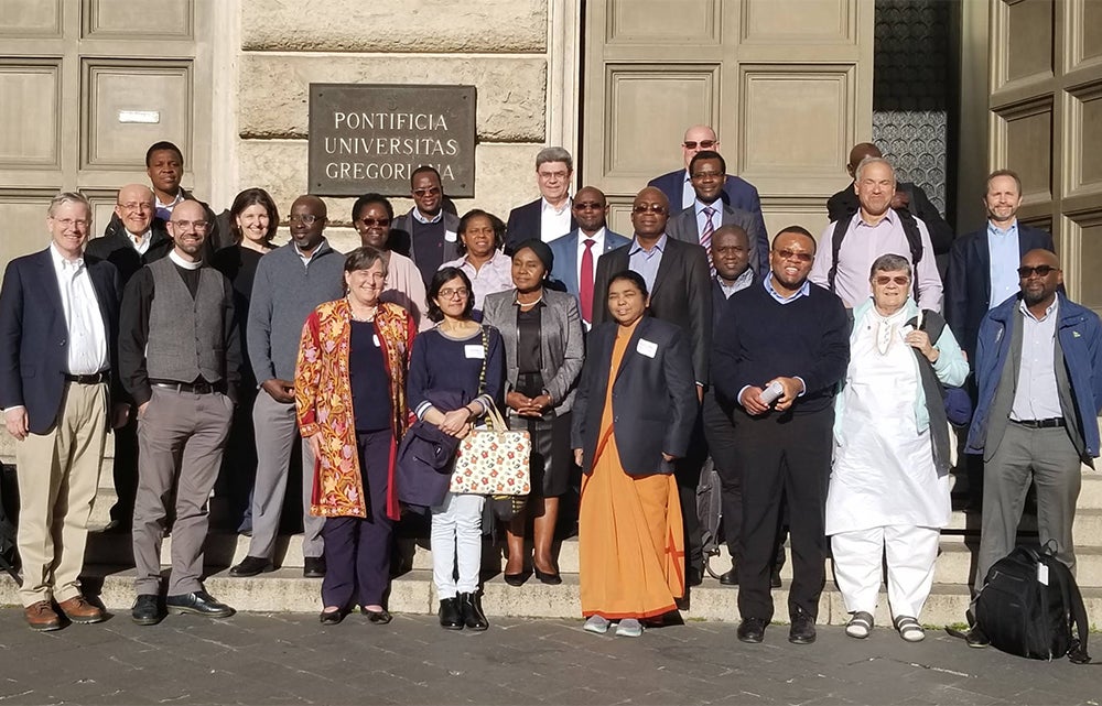 A group of people stand on the steps outside Pontifical University in Rome