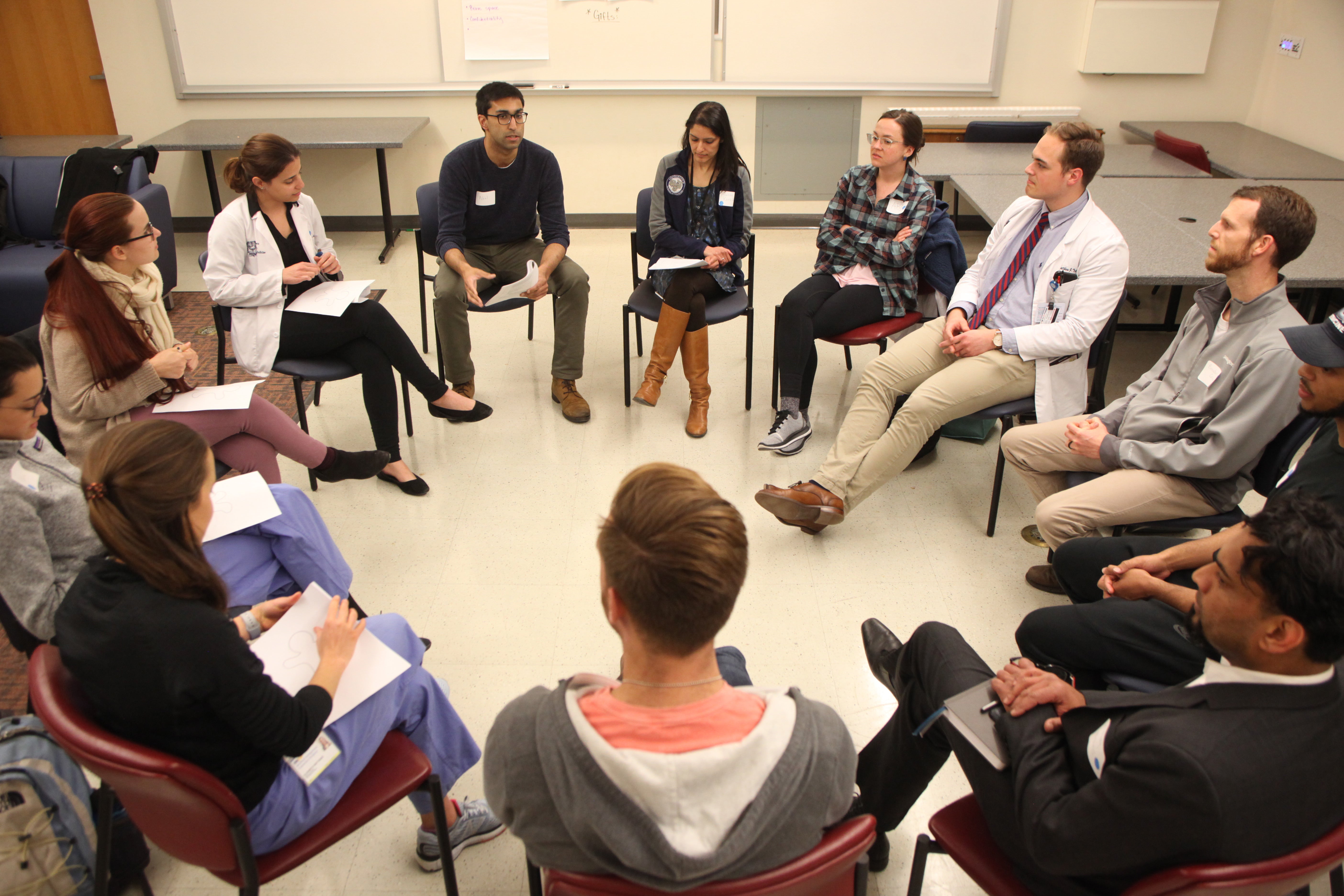 Students sit in a circle in a room.