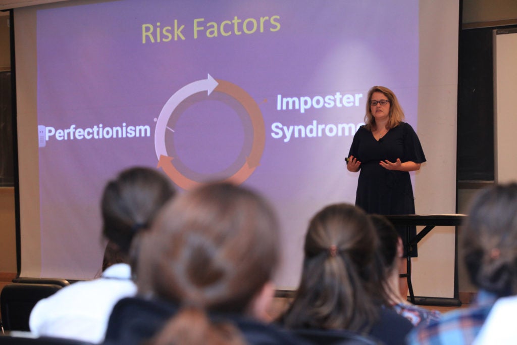 A woman is giving a presentation before an audience. 