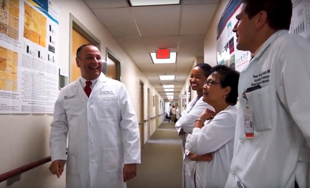 Several physicians in white coats stand in a hallway talking