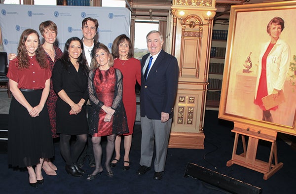 Members of the Ramey family stand together next to the portrait of Estelle Ramey, MD