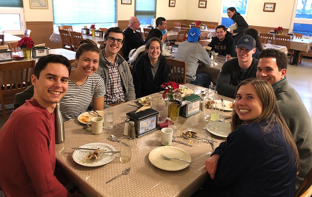 A group of students sit around a table where they have just shared a meal