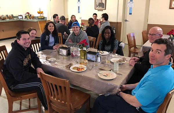 A group of people sit around a table where they have just shared a meal.