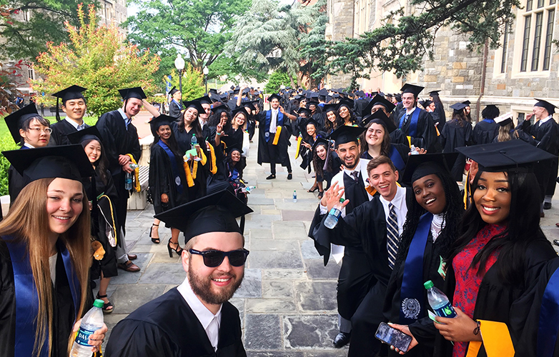 Students in academic regalia outdoors celebrating graduation