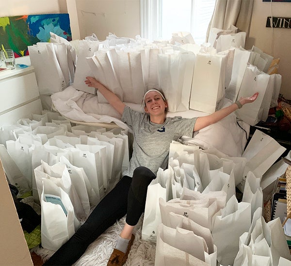 Hofley reclines with arms outstretched; she is surrounded by many white bags.