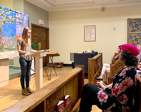 A woman speaks from a podium to an audience