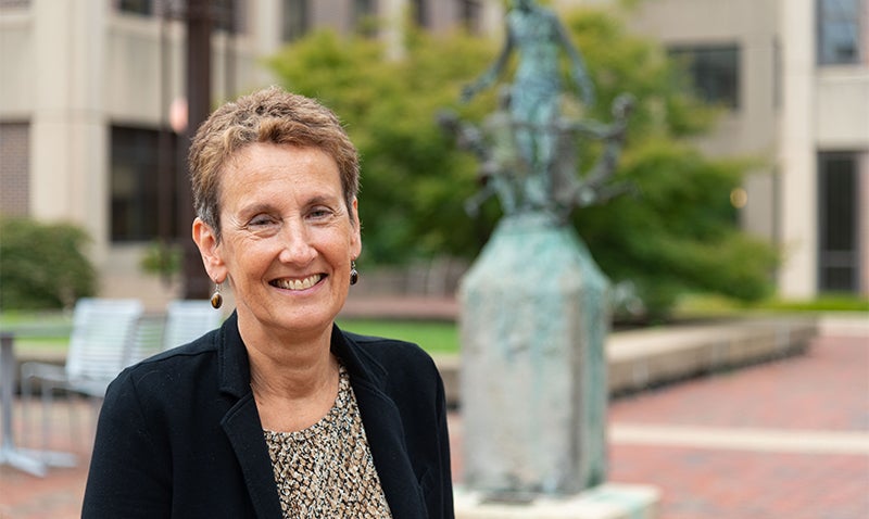 Anna Riegel stands outdoors near a statue