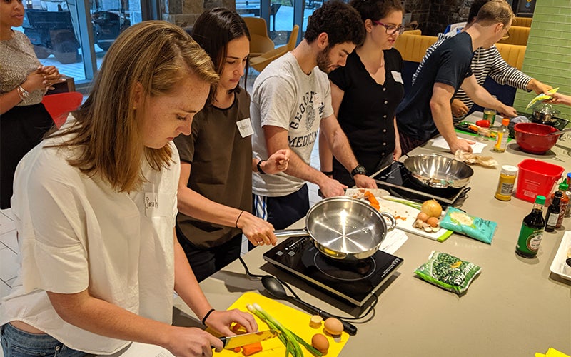 Individuals prepare food at a long counter