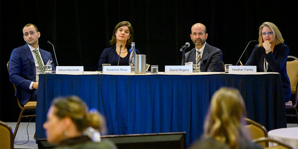 Four people sit at a table before an audience