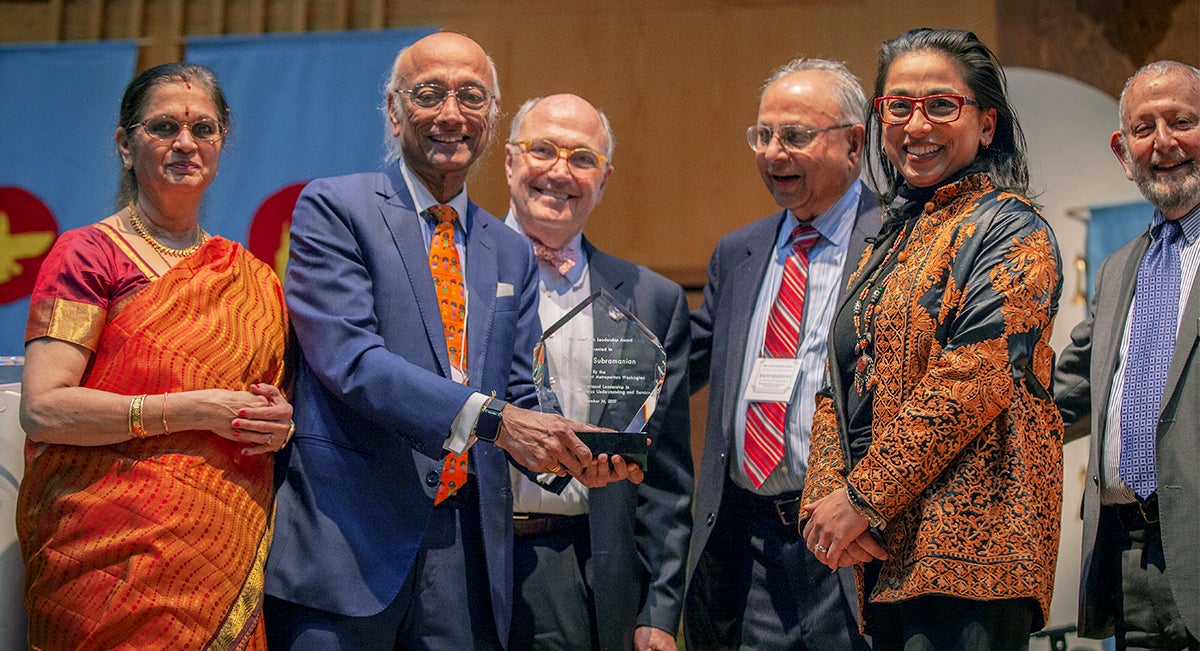 A group of people stand on a stage with the award winner